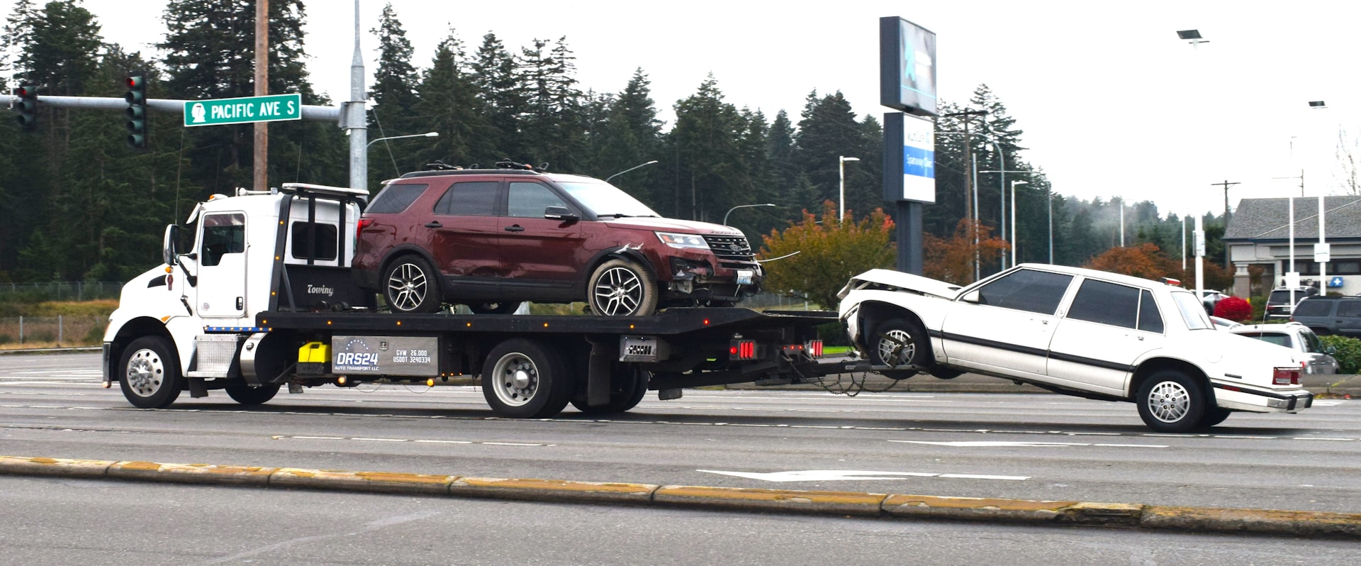 Damaged cars being towed after a California car accident at an intersection, showing post-crash vehicle removal